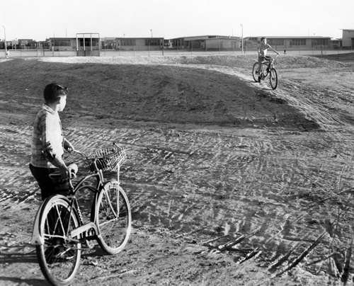 Boys with bikes wait at empty park site