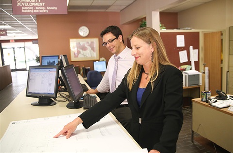 Two employees reviewing a set of plans