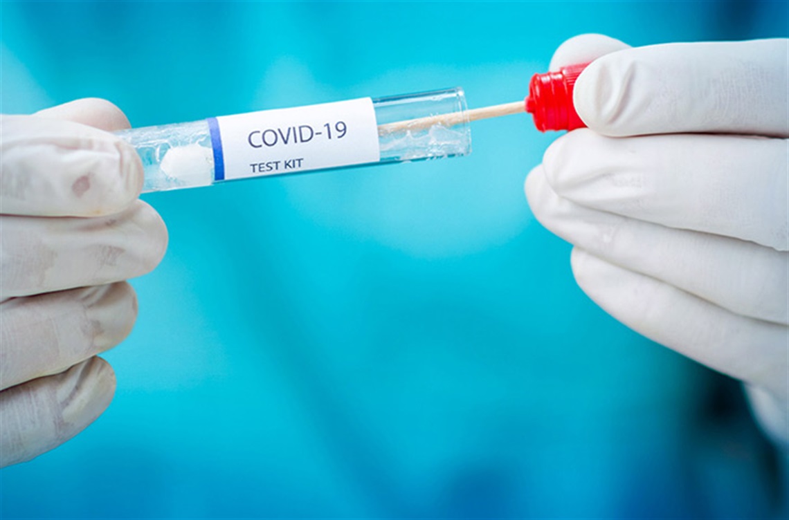 Gloved hands holding COVID swab test kit