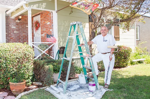 Smiling house painter standing next to ladder 