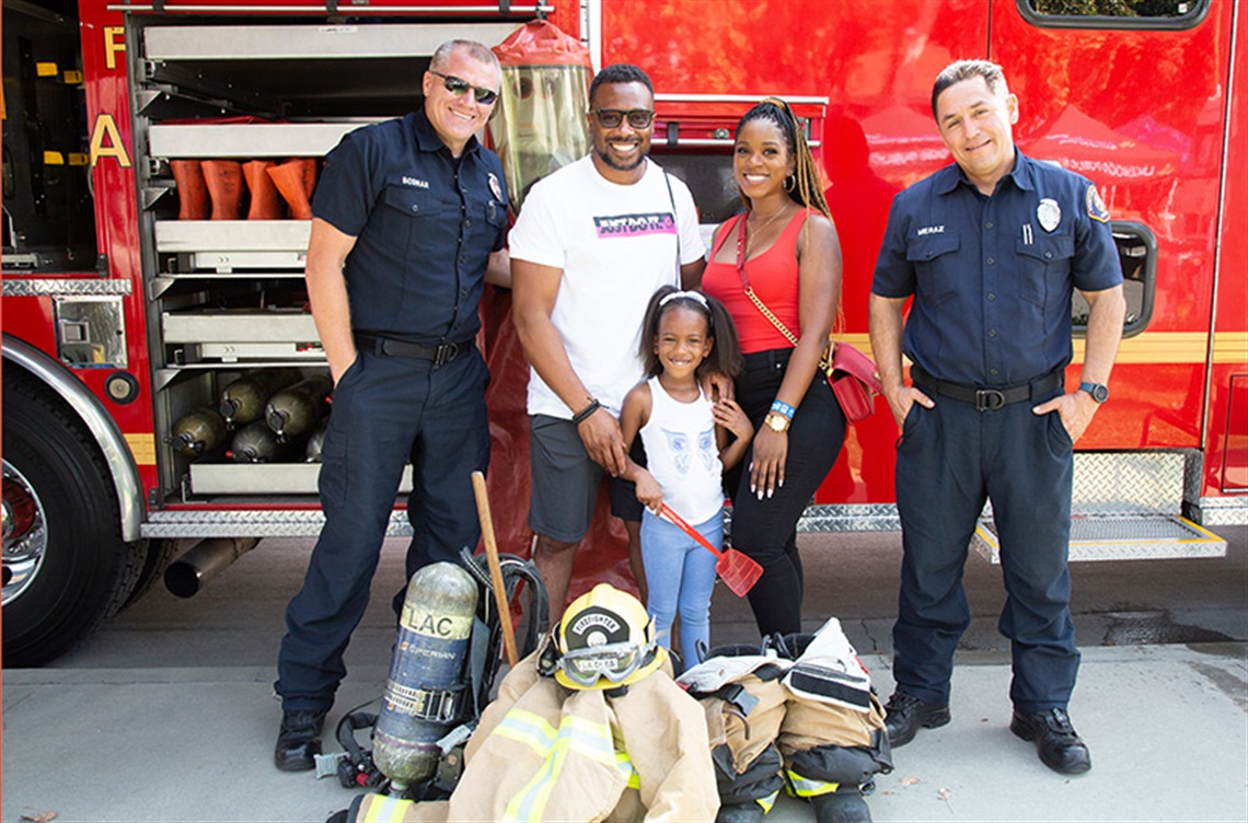 Smiling family with firefighters in front of fire truck