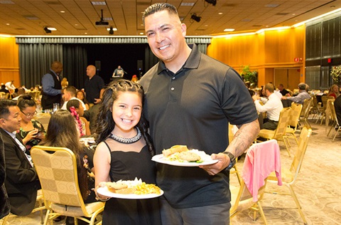 Father and daughter holding dinner plates at event