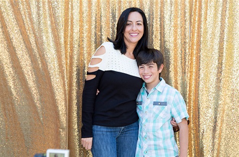 Mother and son in front of gold curtain at event
