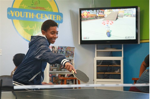 Teen playing ping pong at youth center