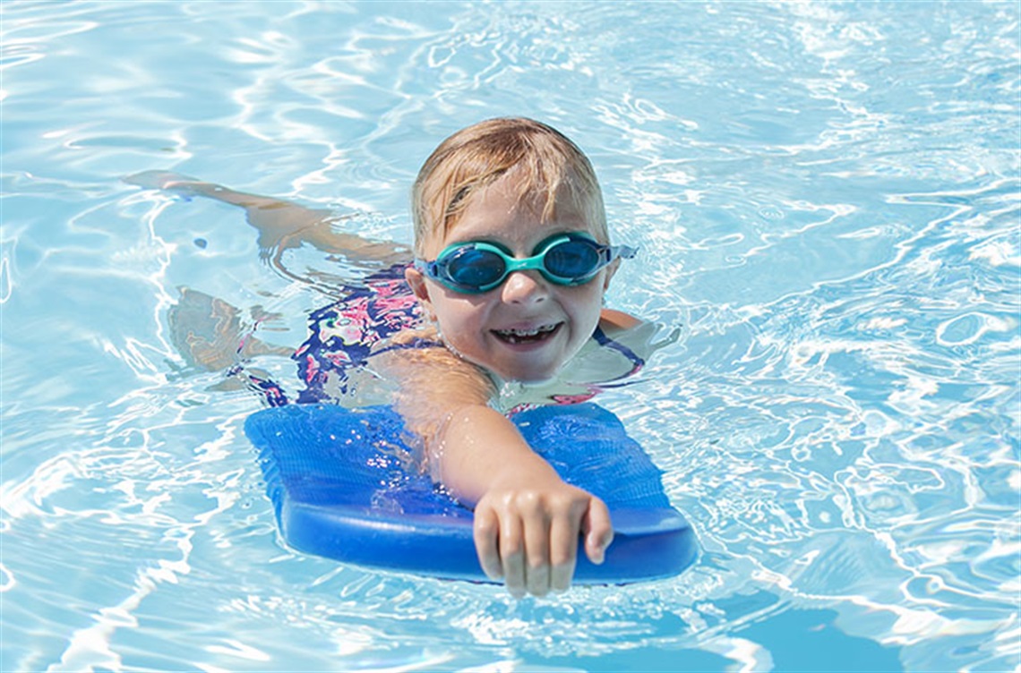 Child wearing swim goggles in pool