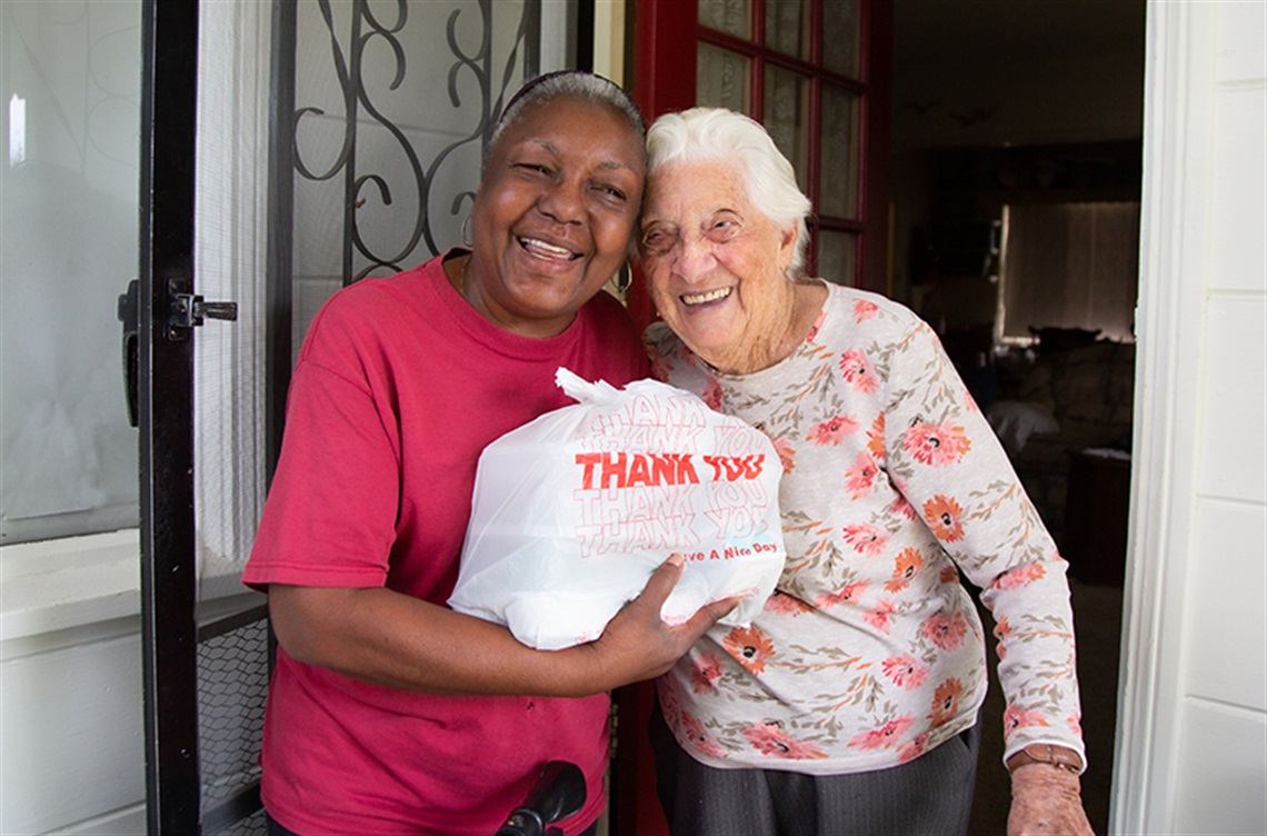 Volunteer and client enjoying a smile during meal delivery